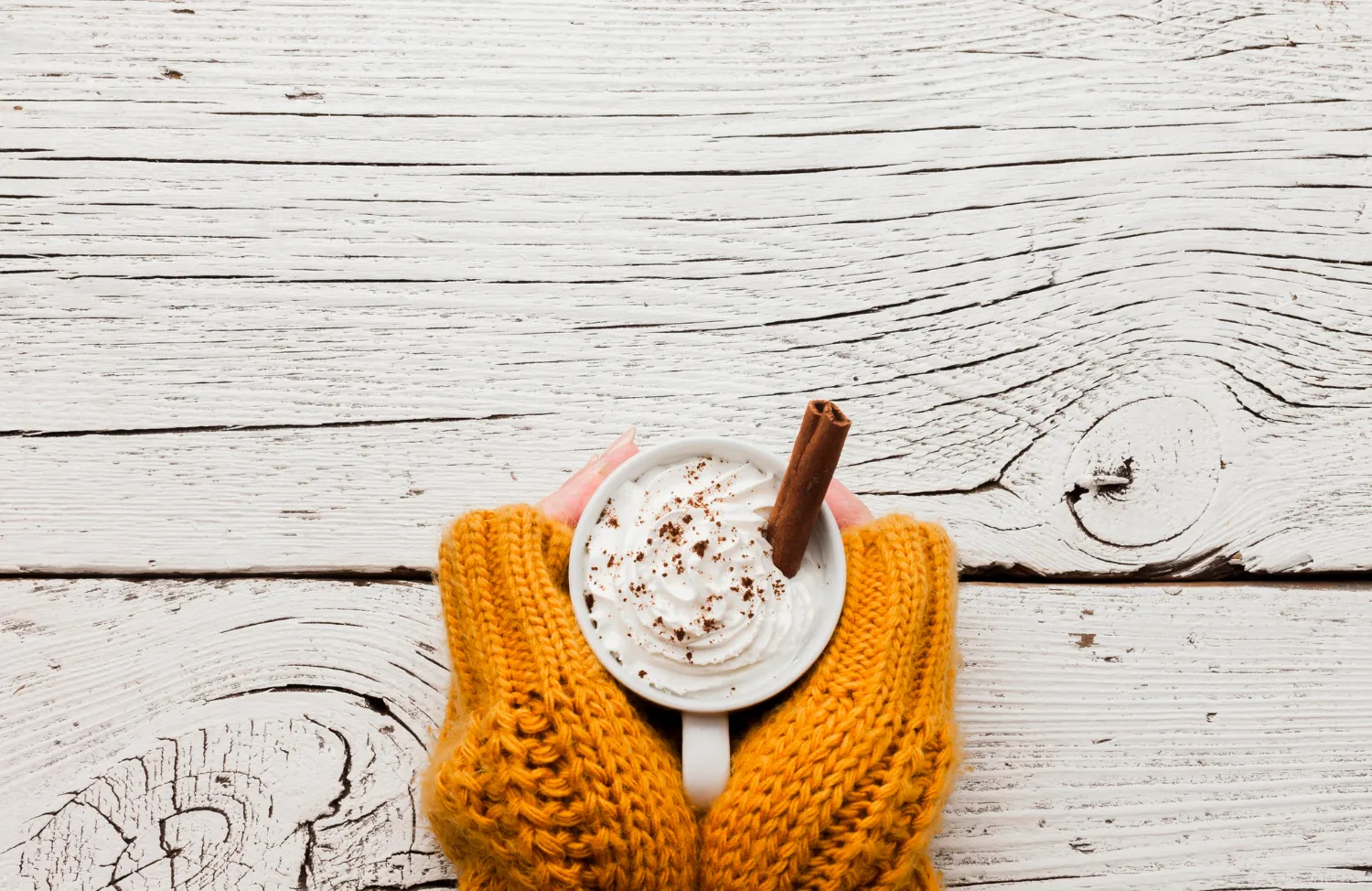 Hands in yellow sweater holding coffee