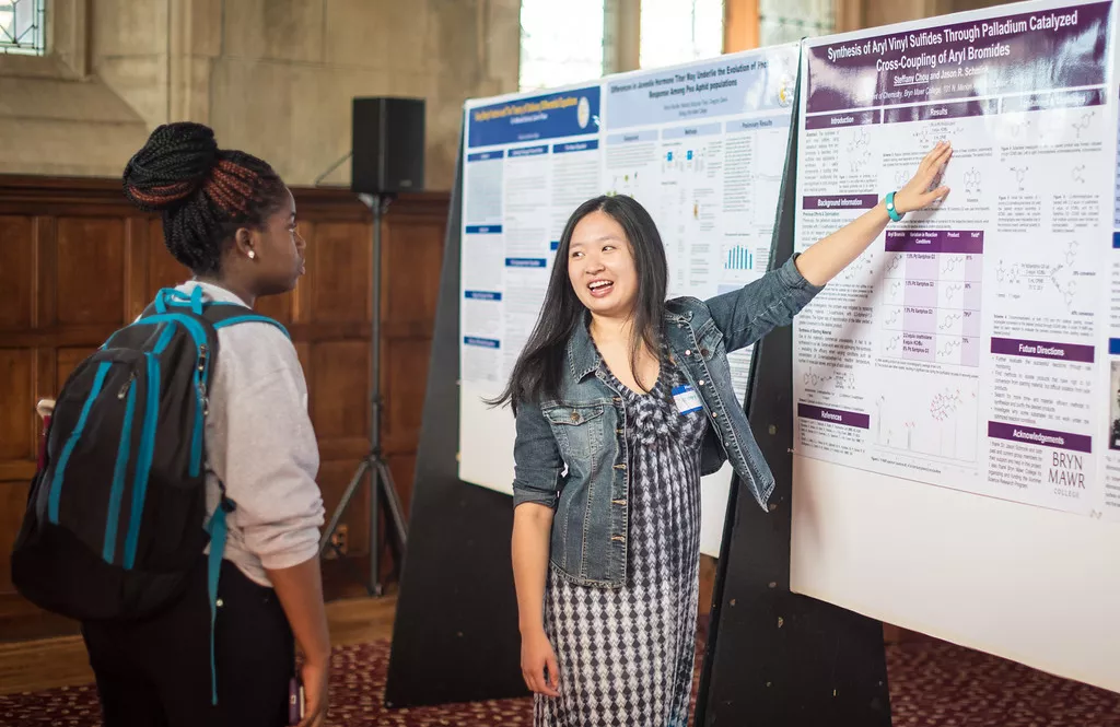 Student shows a poster while another student looks on