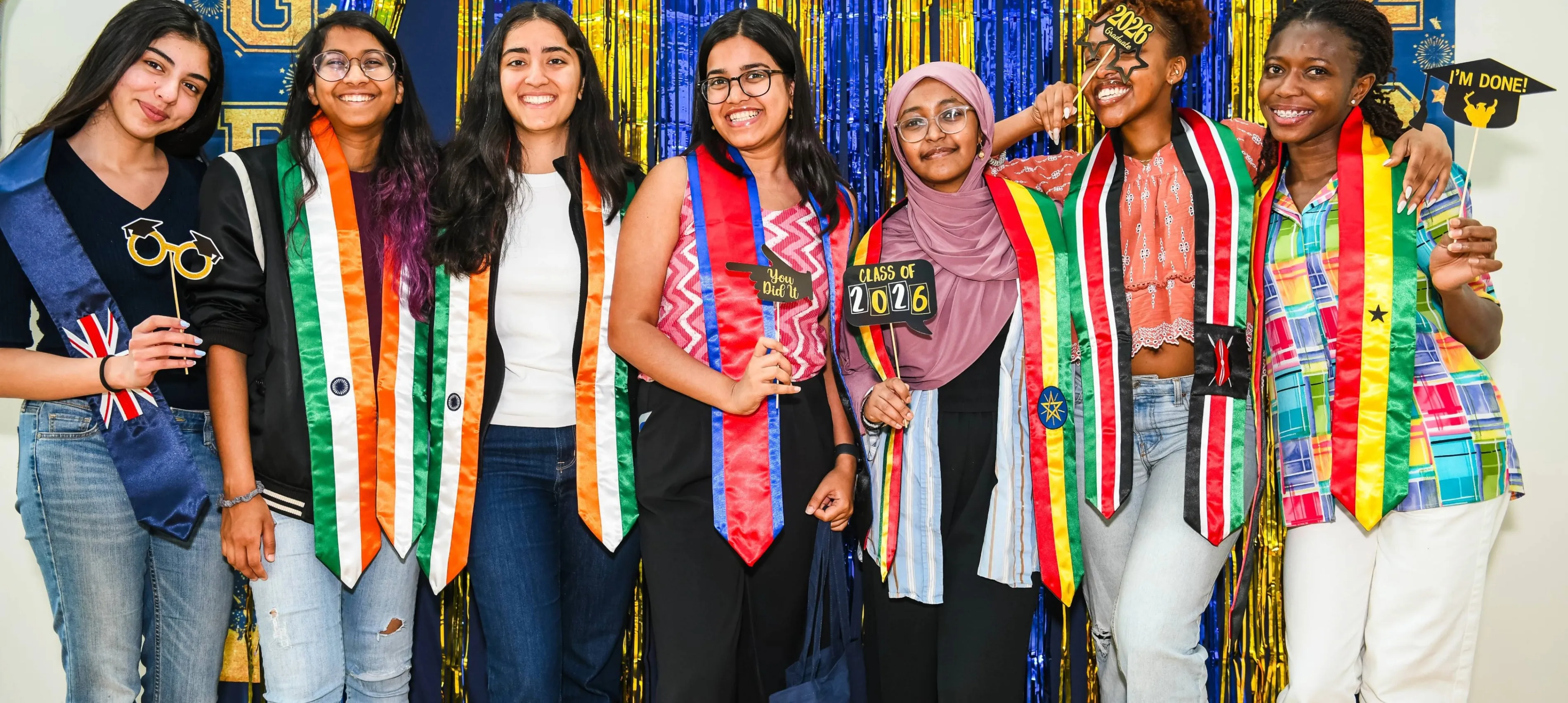 Graduating ISSA Students in front of photo wall with country stoles