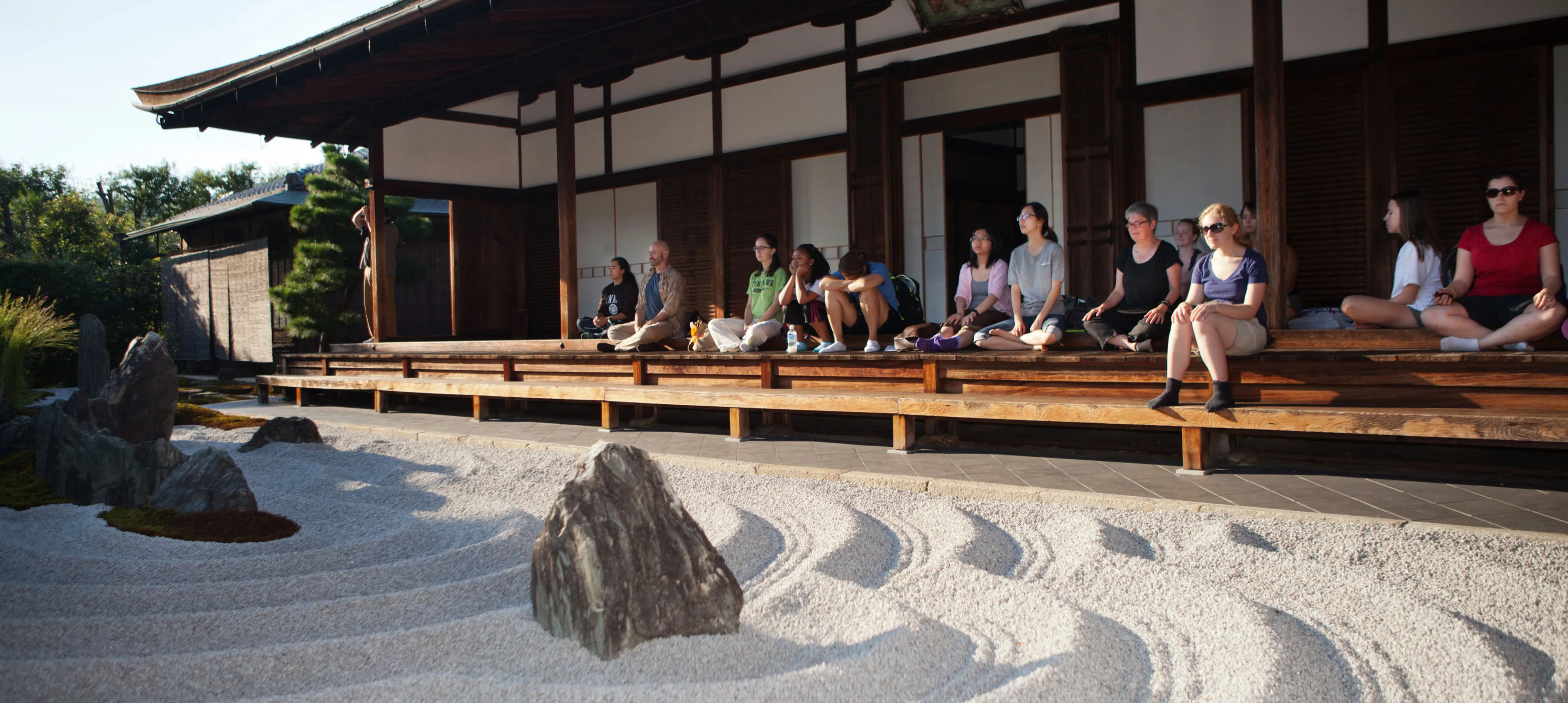 A group of East Asian Studies students and professors meditate in a zen garden in Japan
