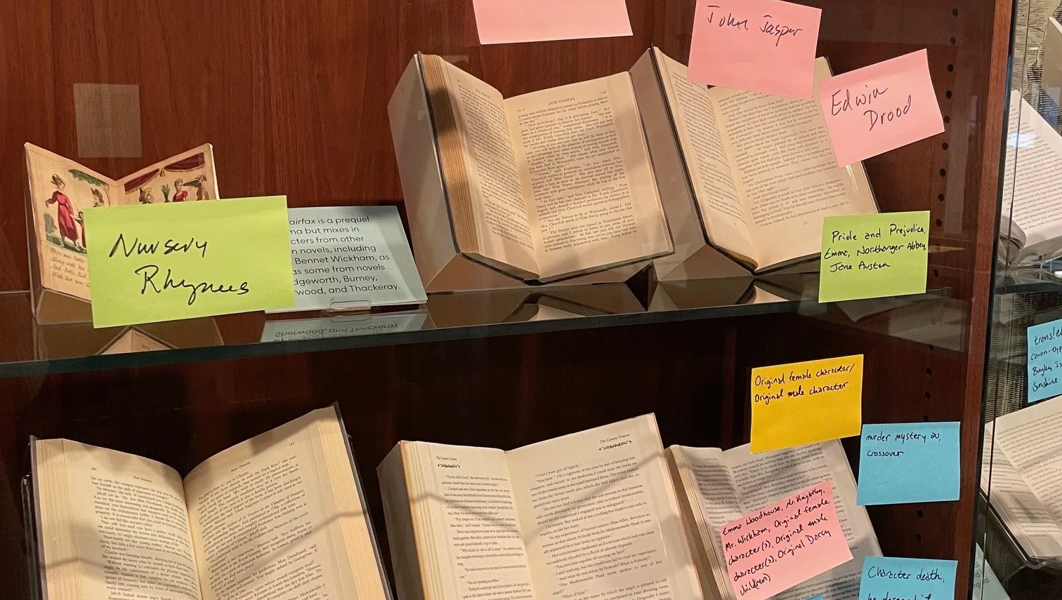 Exhibition case containing books with colorful post-it notes containing fanfiction tags attached the glass case. 
