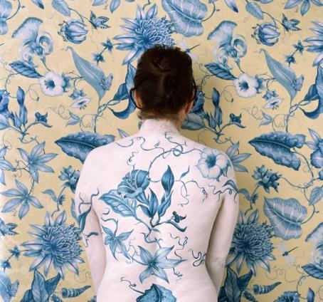 Cecilia Paredes painted to match the ornate floral backdrop against which she stands looking away