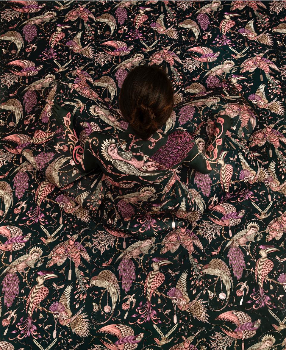 Cecilia Paredes photographed from above, sitting amidst skirt that fills background with pattern of flora and fauna.