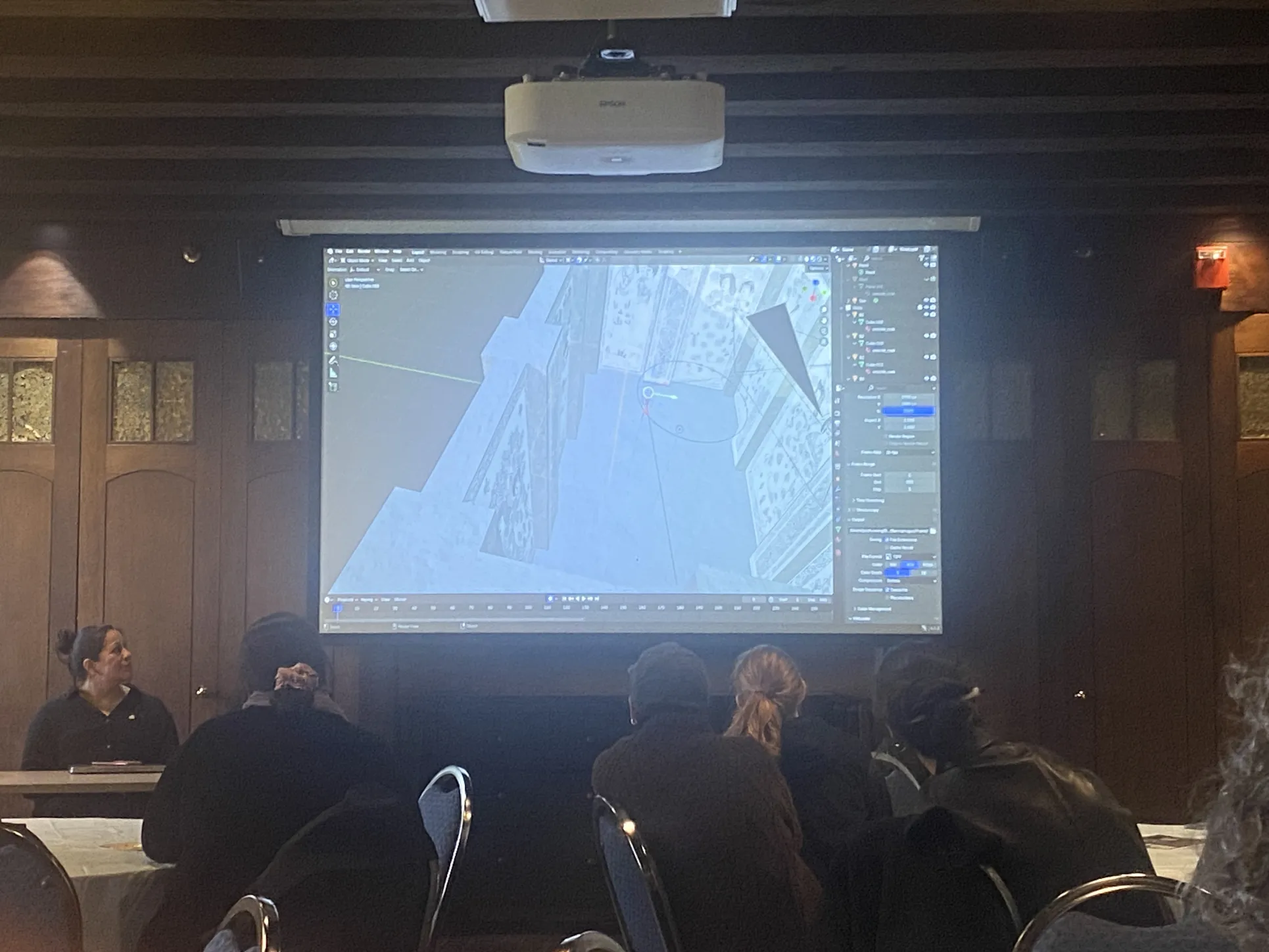 Yuzhu Wang demonstrates her 3D model of an 8th-century Chinese sarcophagus. The model is projected on a screen behind her.