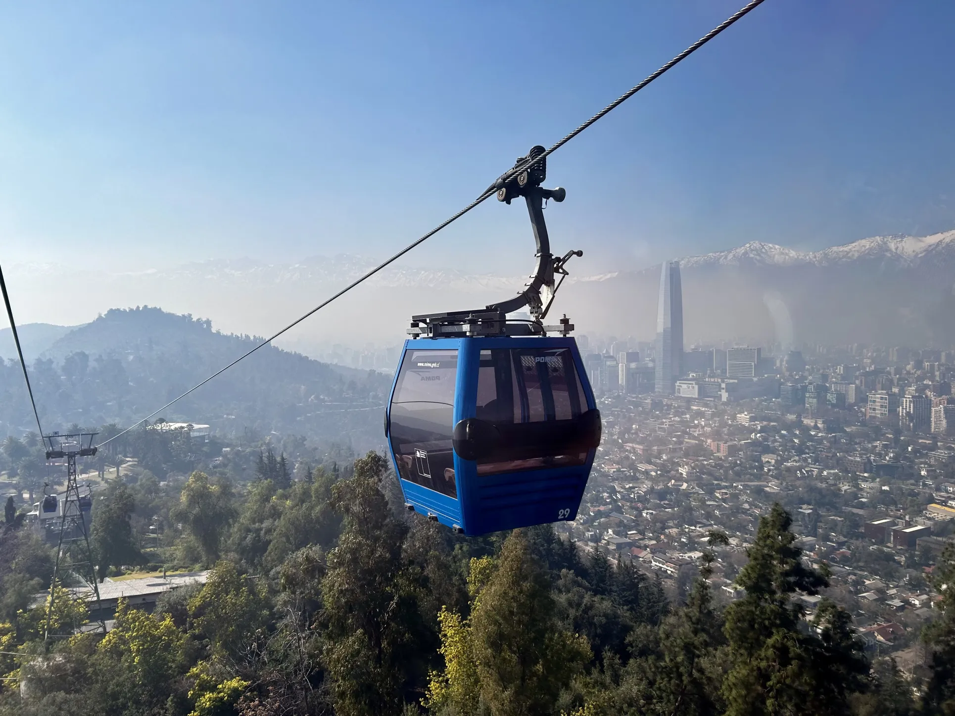 an image of a cable car going up a mountain with a cityscape and mountains behind