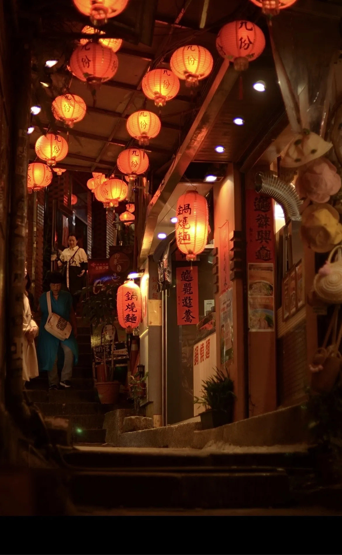 an image of a narrow street in Taiwan at night, lit by many warmly-colored lanterns