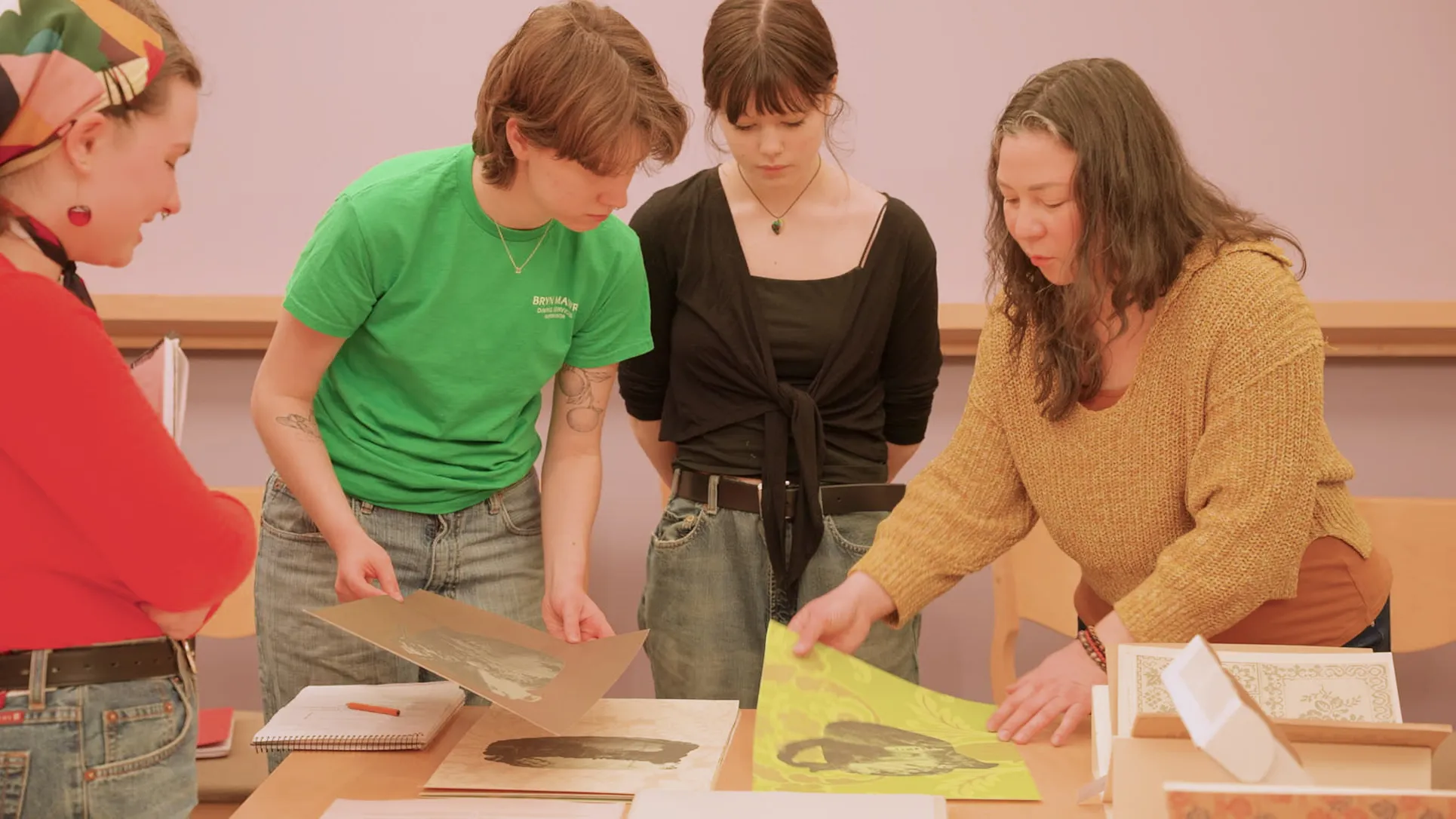 Four women stand around East Asian texts