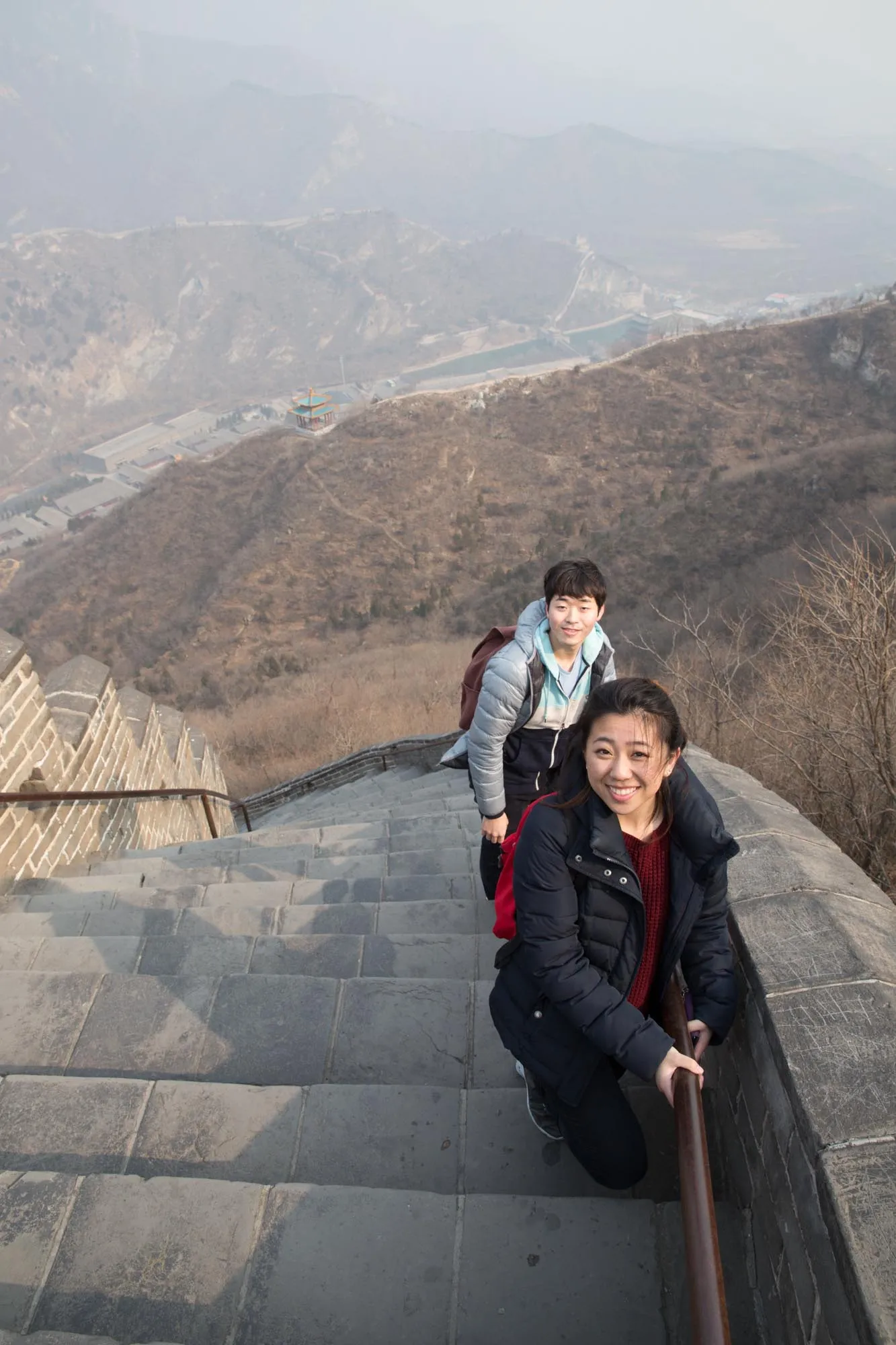 A young man and a young woman in winter clothes climb the Great Wall of China