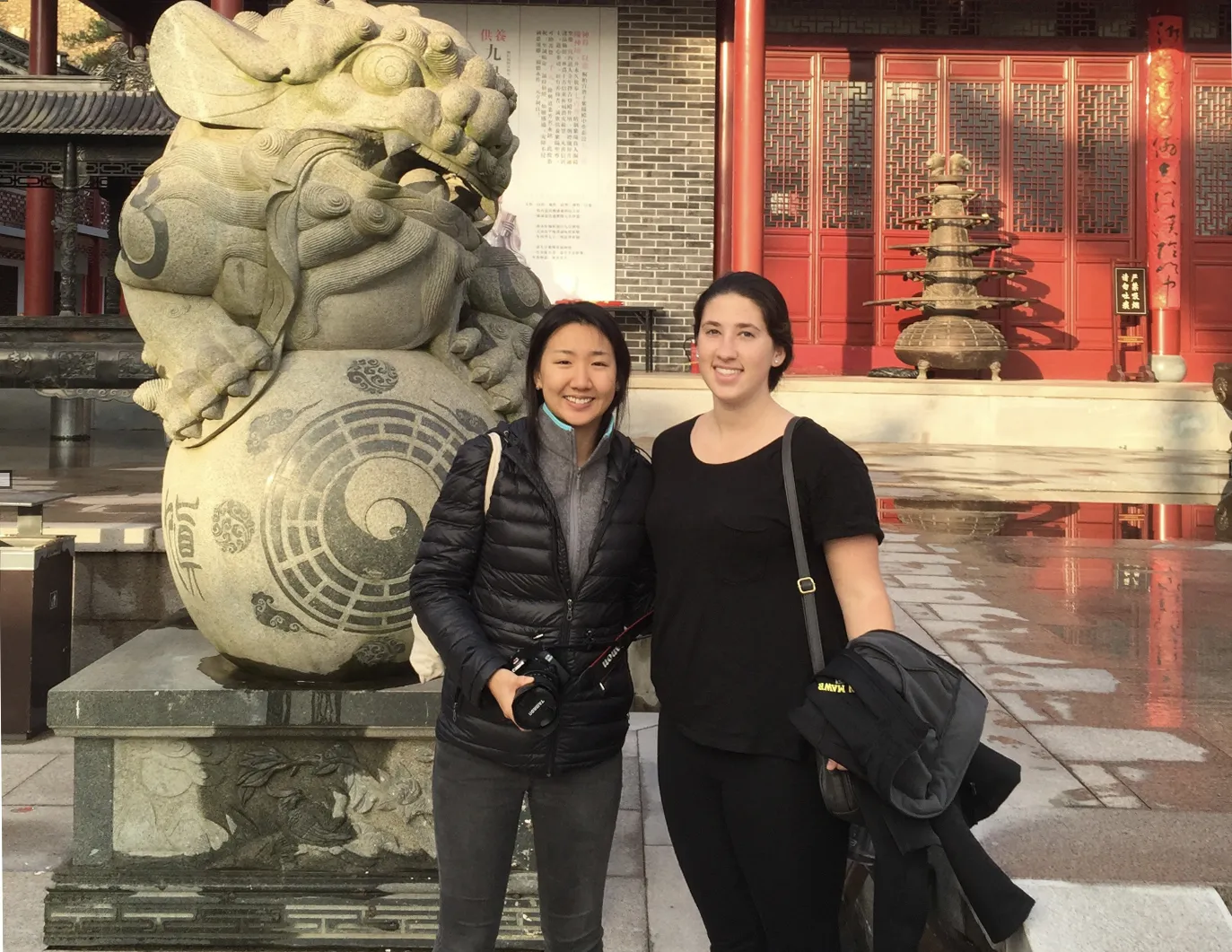 A Bryn Mawr College student studying abroad in China poses in front of a temple with a friend