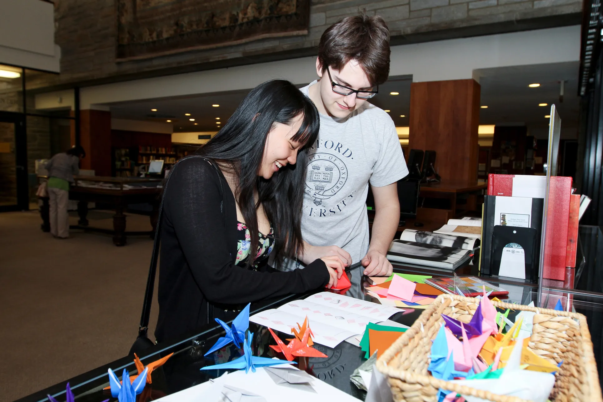 A young man and young woman try origami as a part of a Bi-Co East Asian Languages and Cultures program