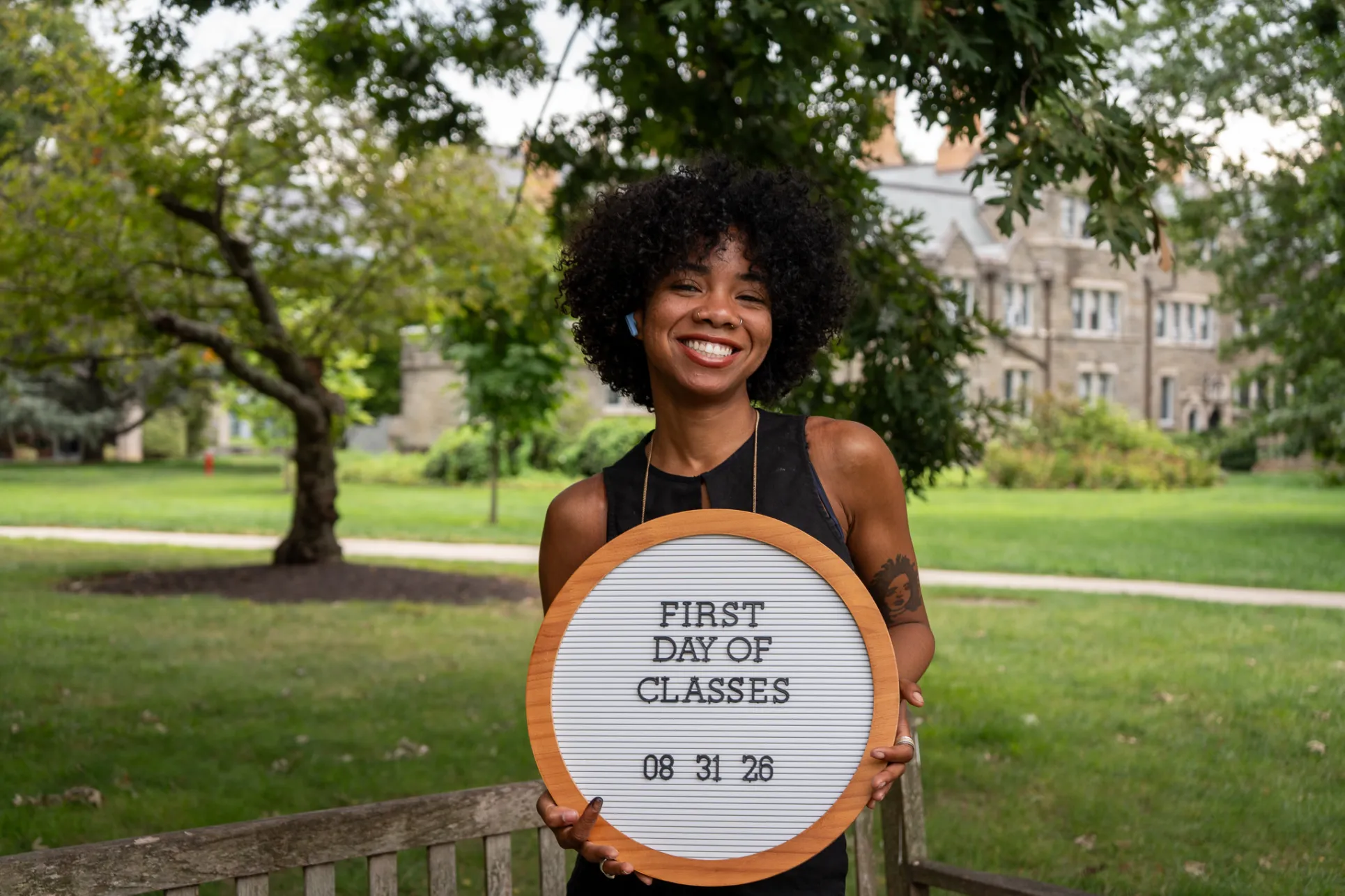 student holding a first day of classes sign