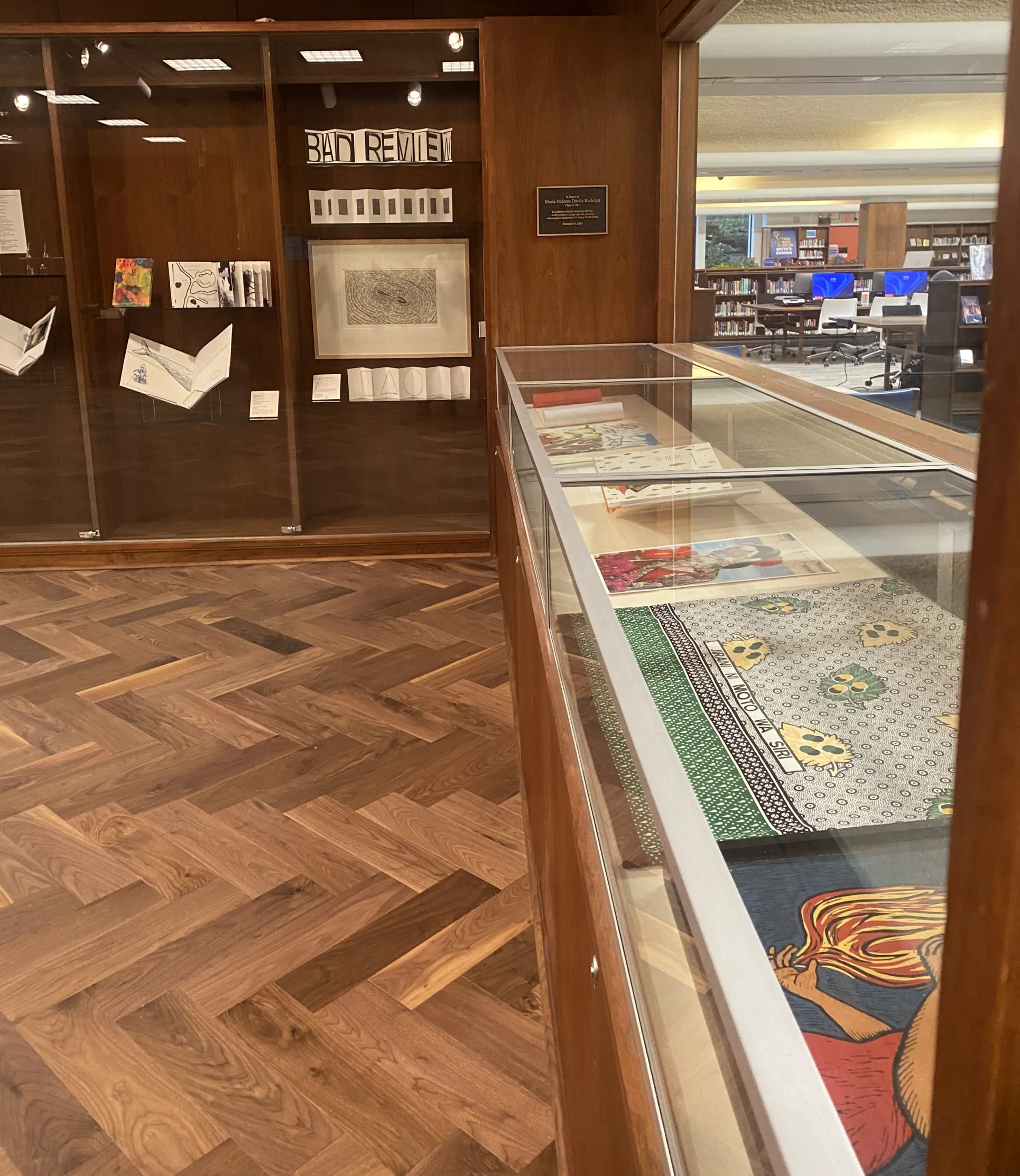 Display cases in a gallery containing art and books.