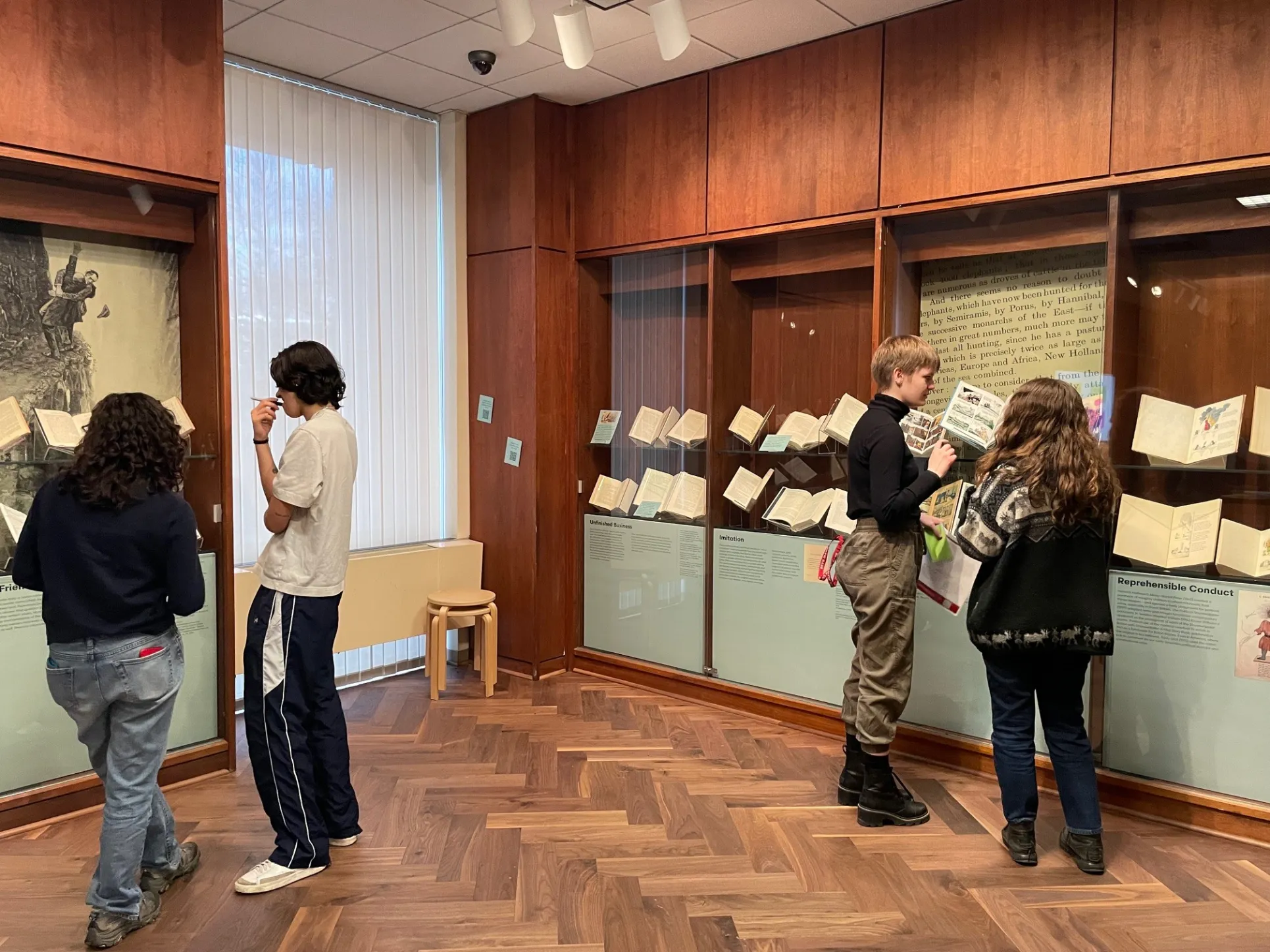 Students viewing exhibition cases containing books.
