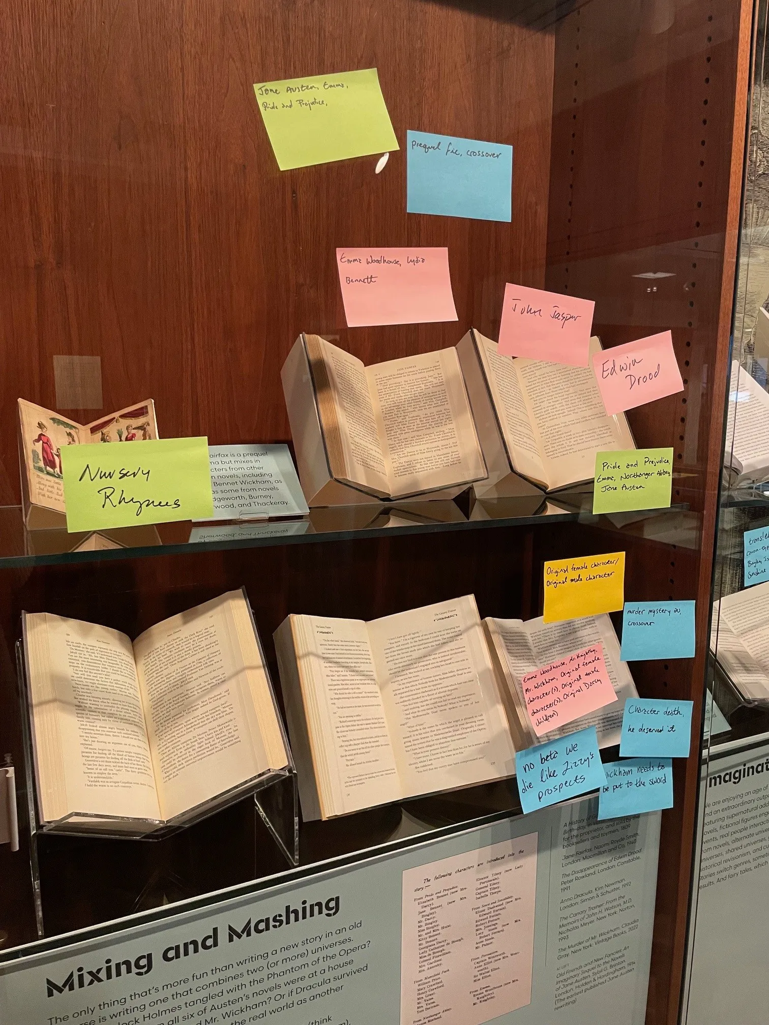 Exhibition case containing books with colorful post-it notes containing fanfiction tags attached the glass case. 