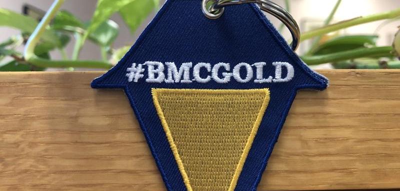 A lantern-shaped keychain with the text "#BMCGOLD."