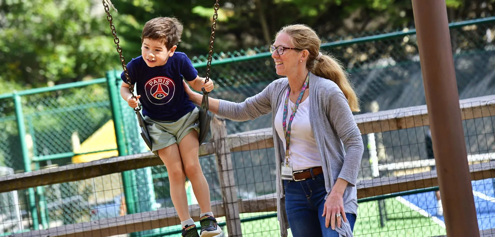 Teacher pushing student on swing