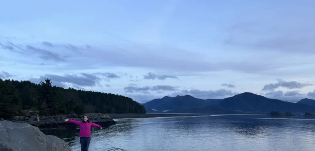 Foregrounded student in pink coat with glacier lake behind her