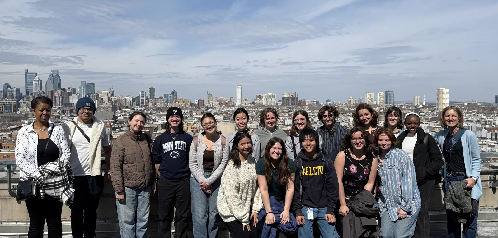 Photo of students standing on the roof of building with skyline in the background.