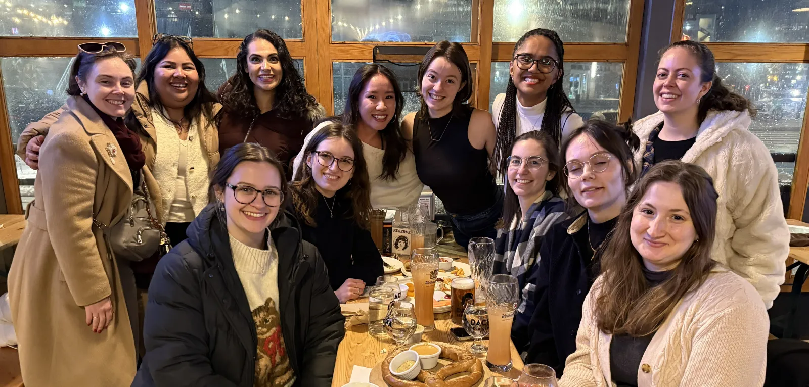 A group of women smile at the camera while standing and sitting around a table