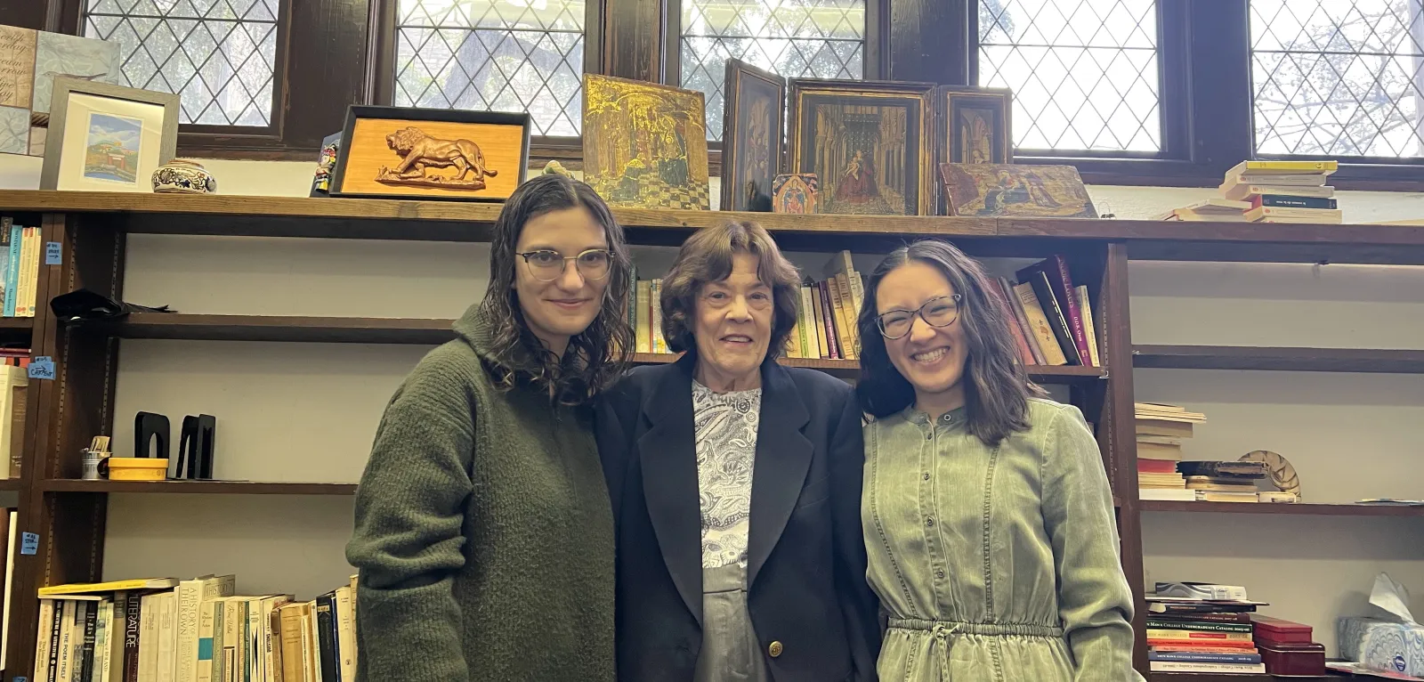 Two students and a professor in an office in Old Library, smiling at the camera