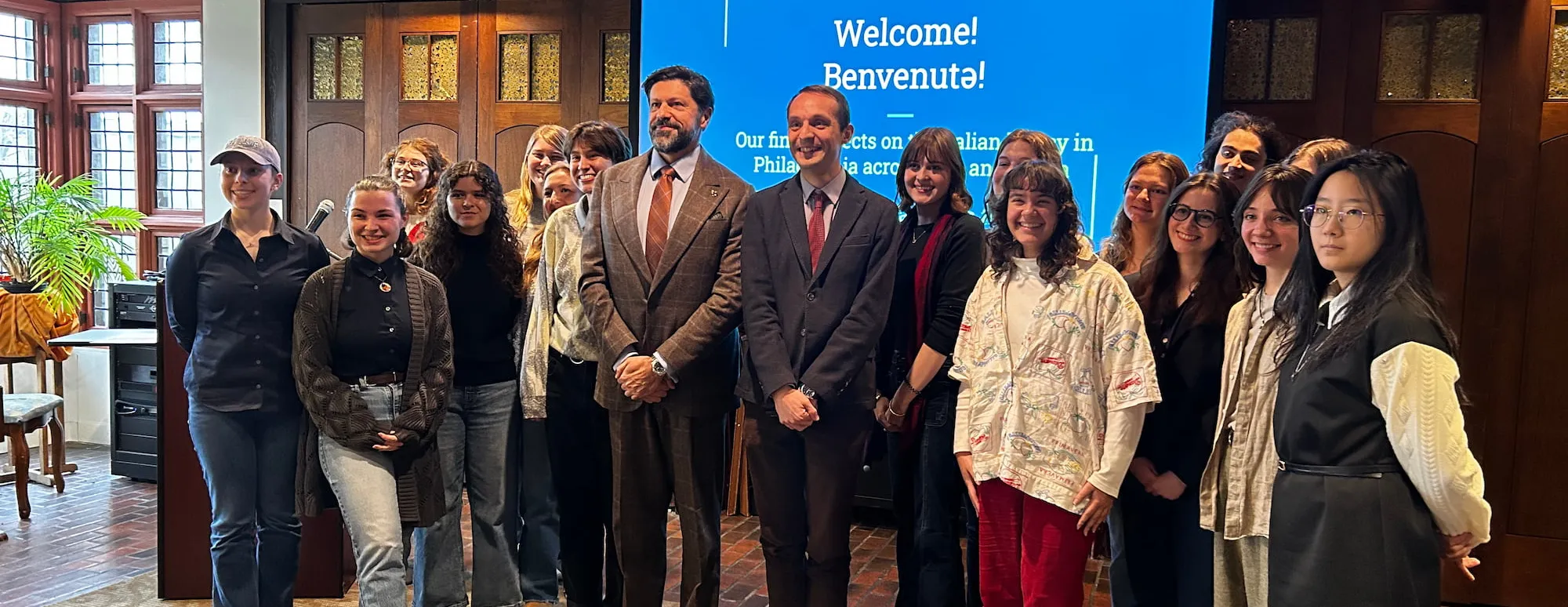 Transnational Italian Studies students stand with a professor in front of a screen