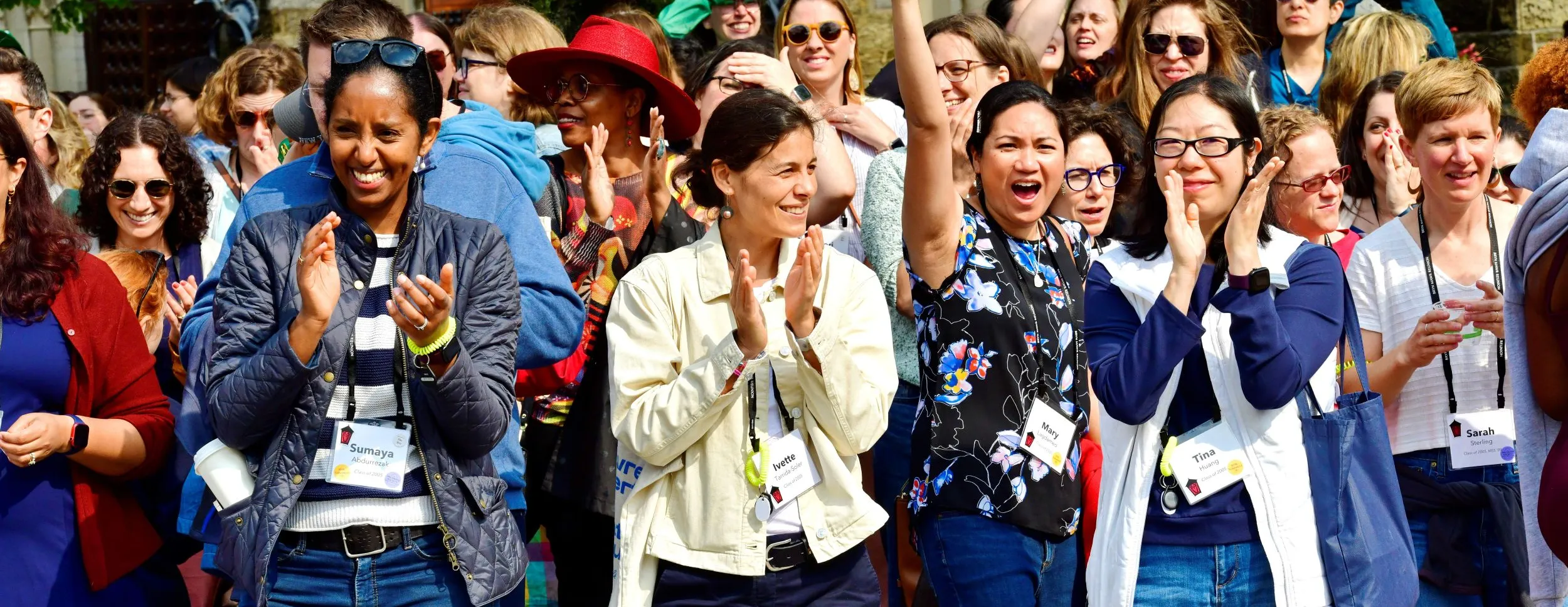 A crowd of woman smile and cheer, with Goodhart Hall visible in the background.