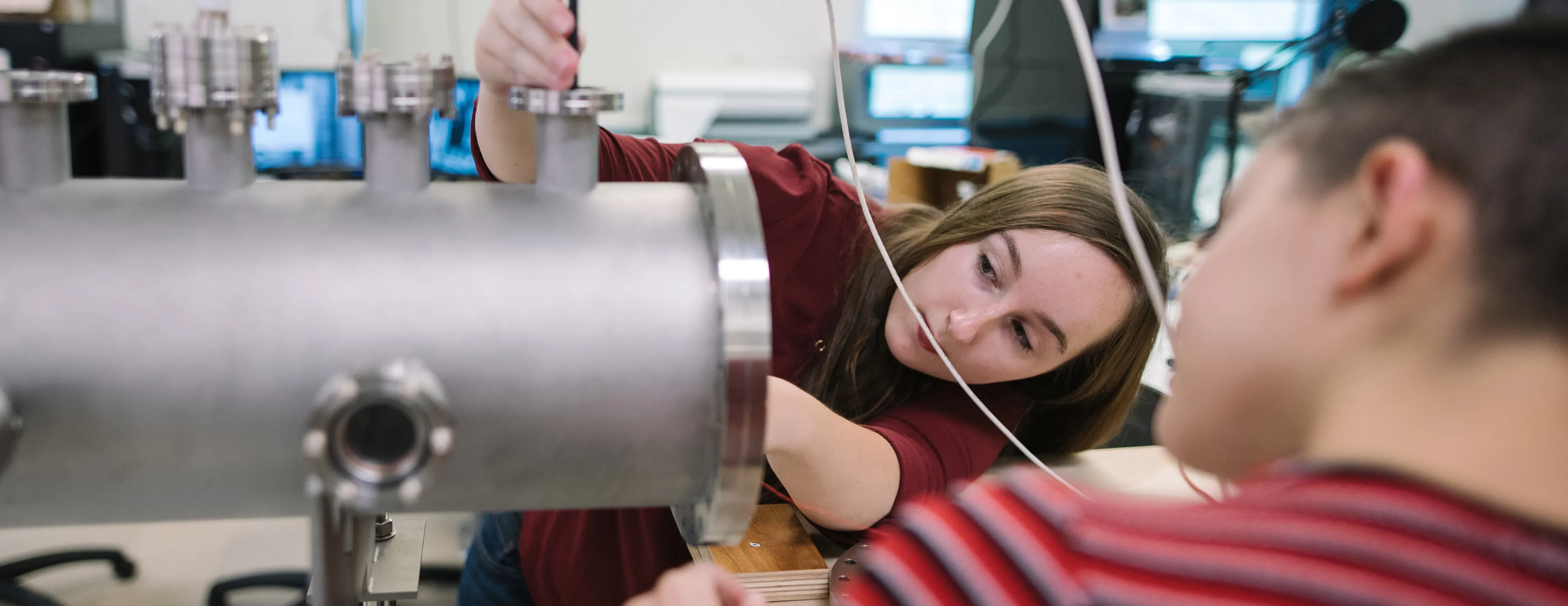 Two physics students work on plasma physics equipment in a lab