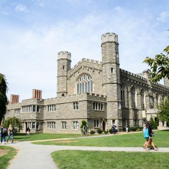 Large stone building with students walking across lawn