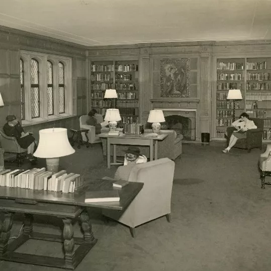 Wood paneled room with students reading in chairs