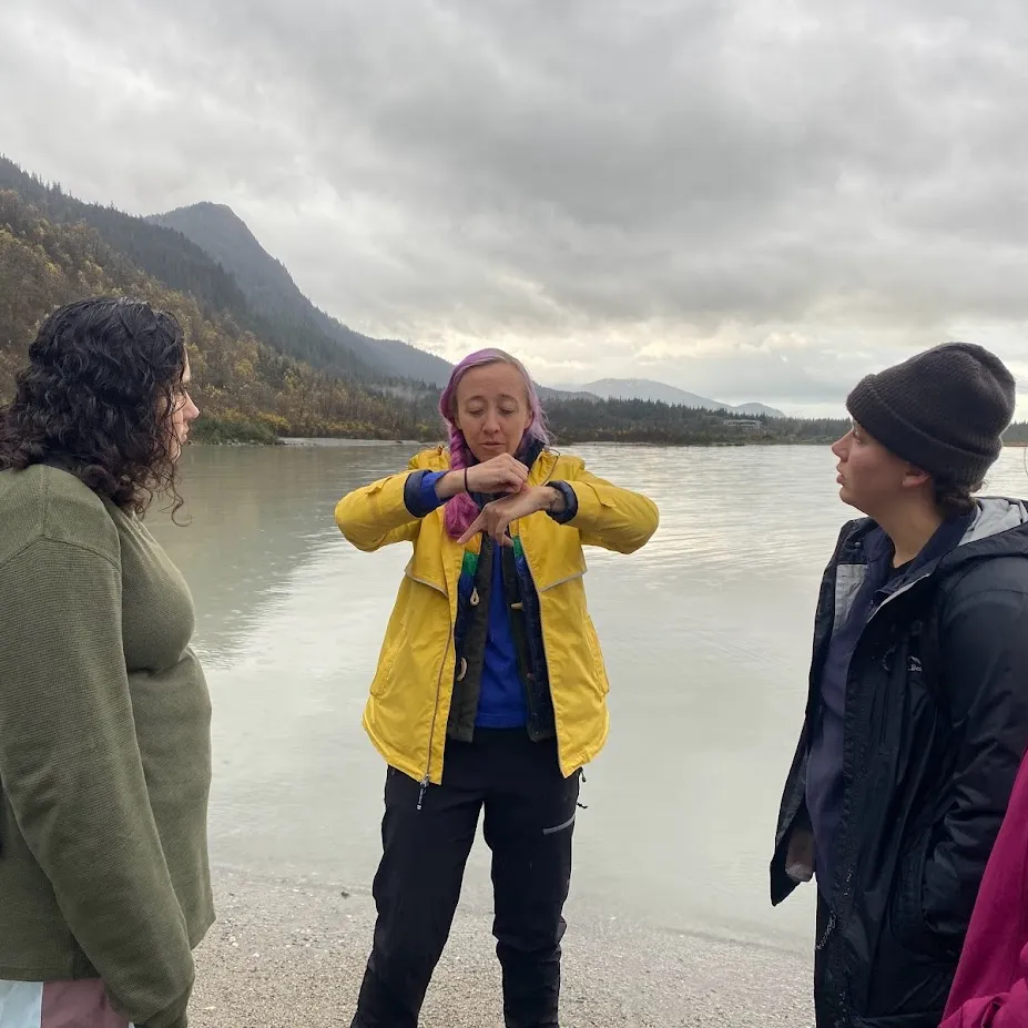 Four people stand in the foreground of a glacier lake