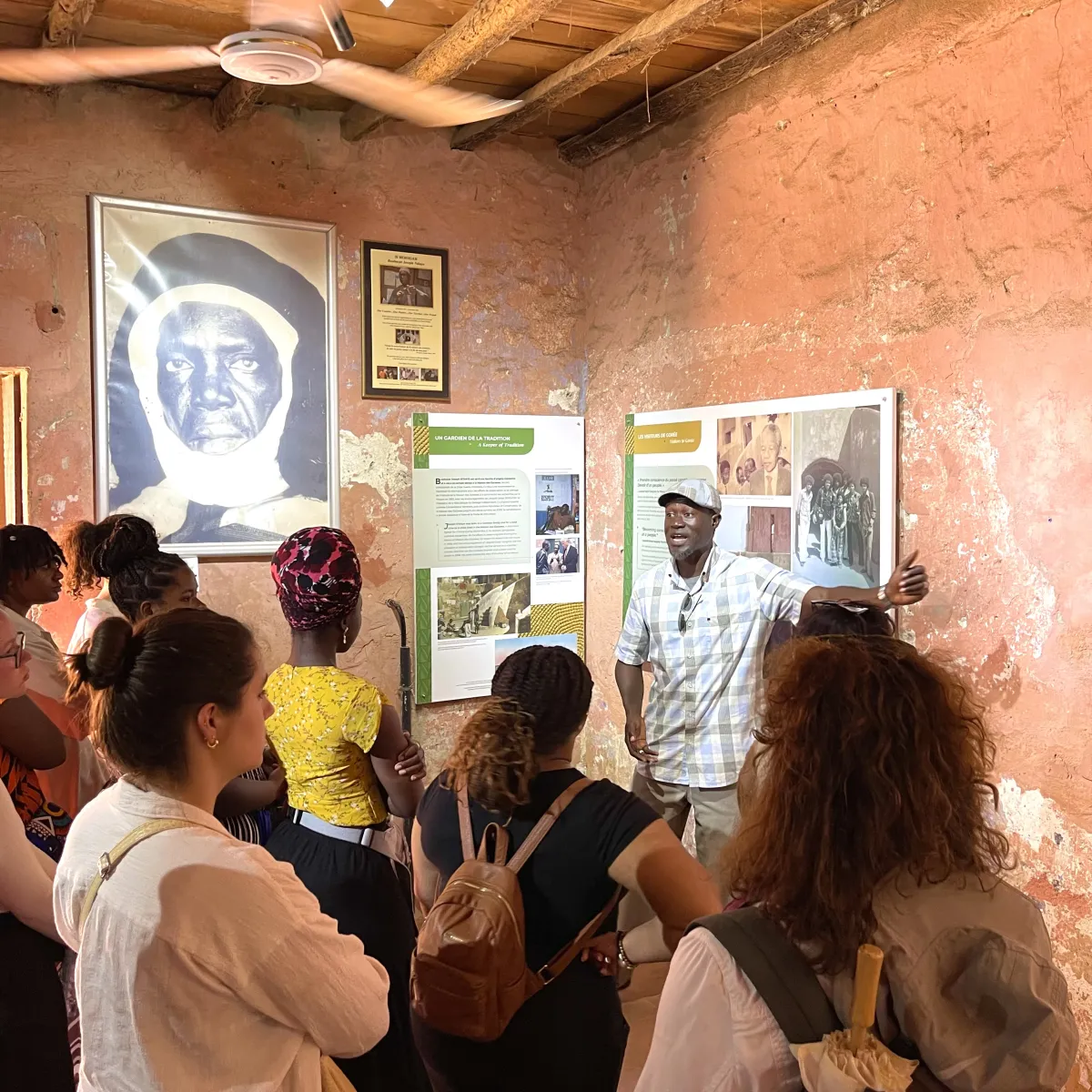 A group of students with their backs to camera listen to a tourguide in a museum.