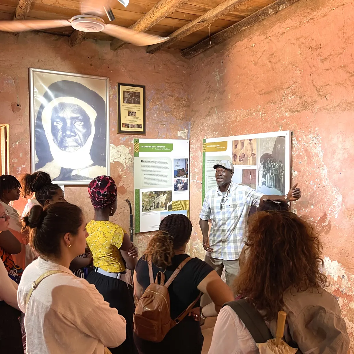 A group of students with their backs to camera listen to a tourguide in a museum.