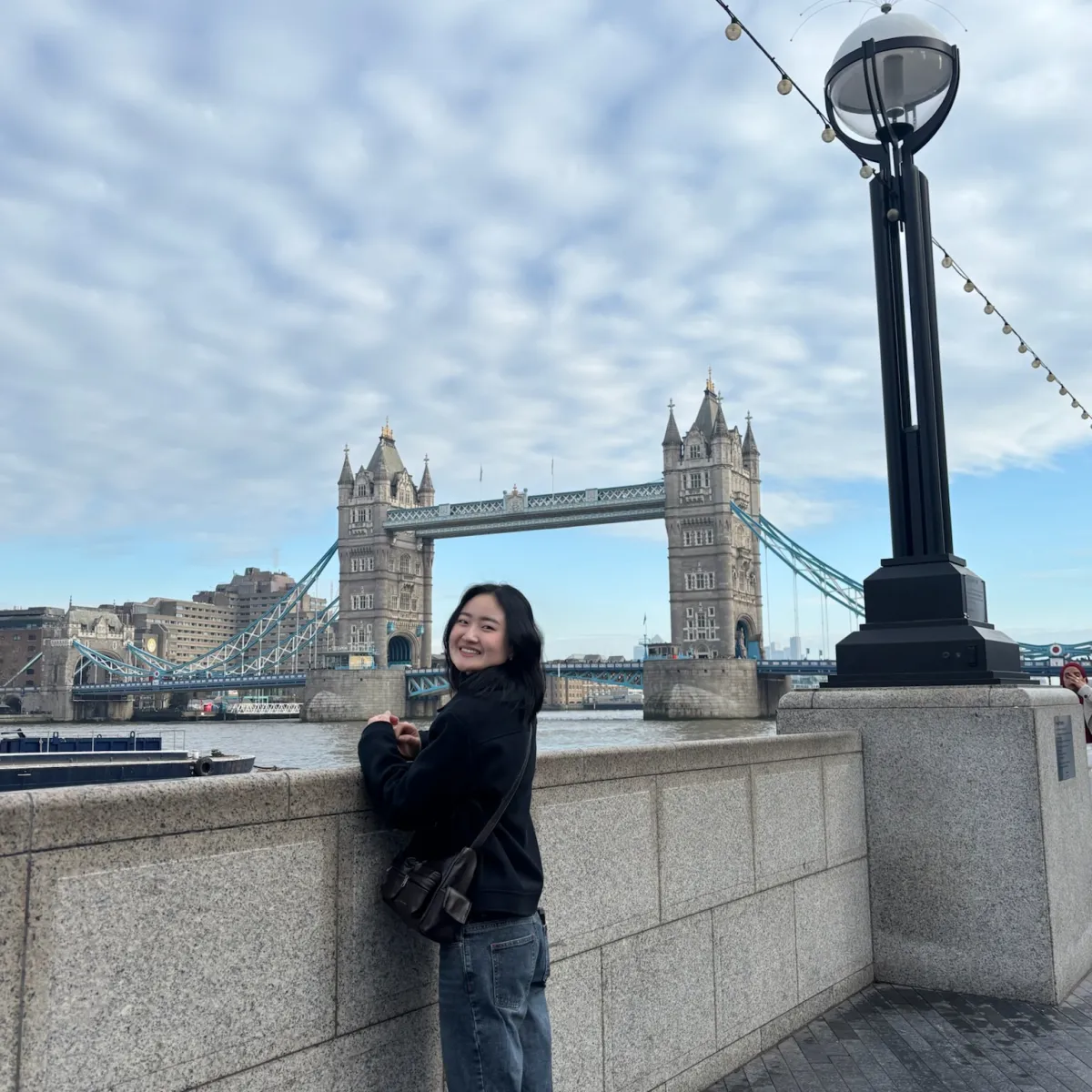 Sophia smiling in front of the Thames river and London Bridge