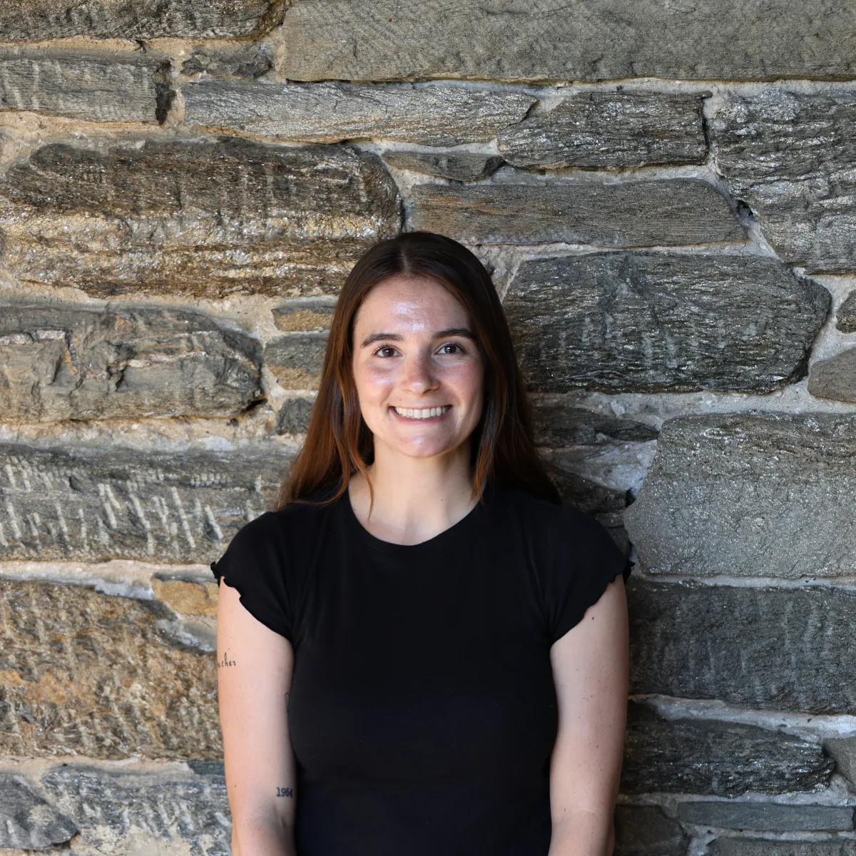 Kristen Lauritzen poses in front of a stone wall