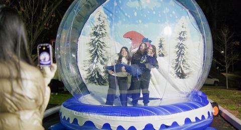 Three students taking a photo in an inflatable snow globe.