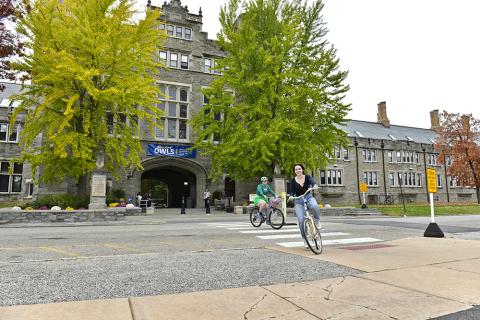 Students riding bicycles in front of Pem Arch