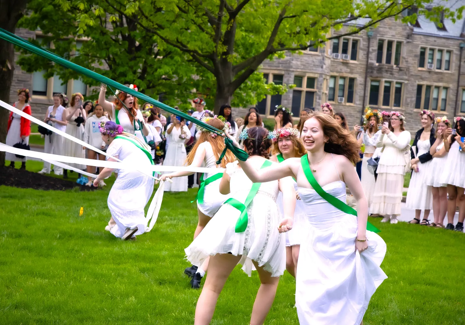 students participating in college traditions by running around the mayday pole