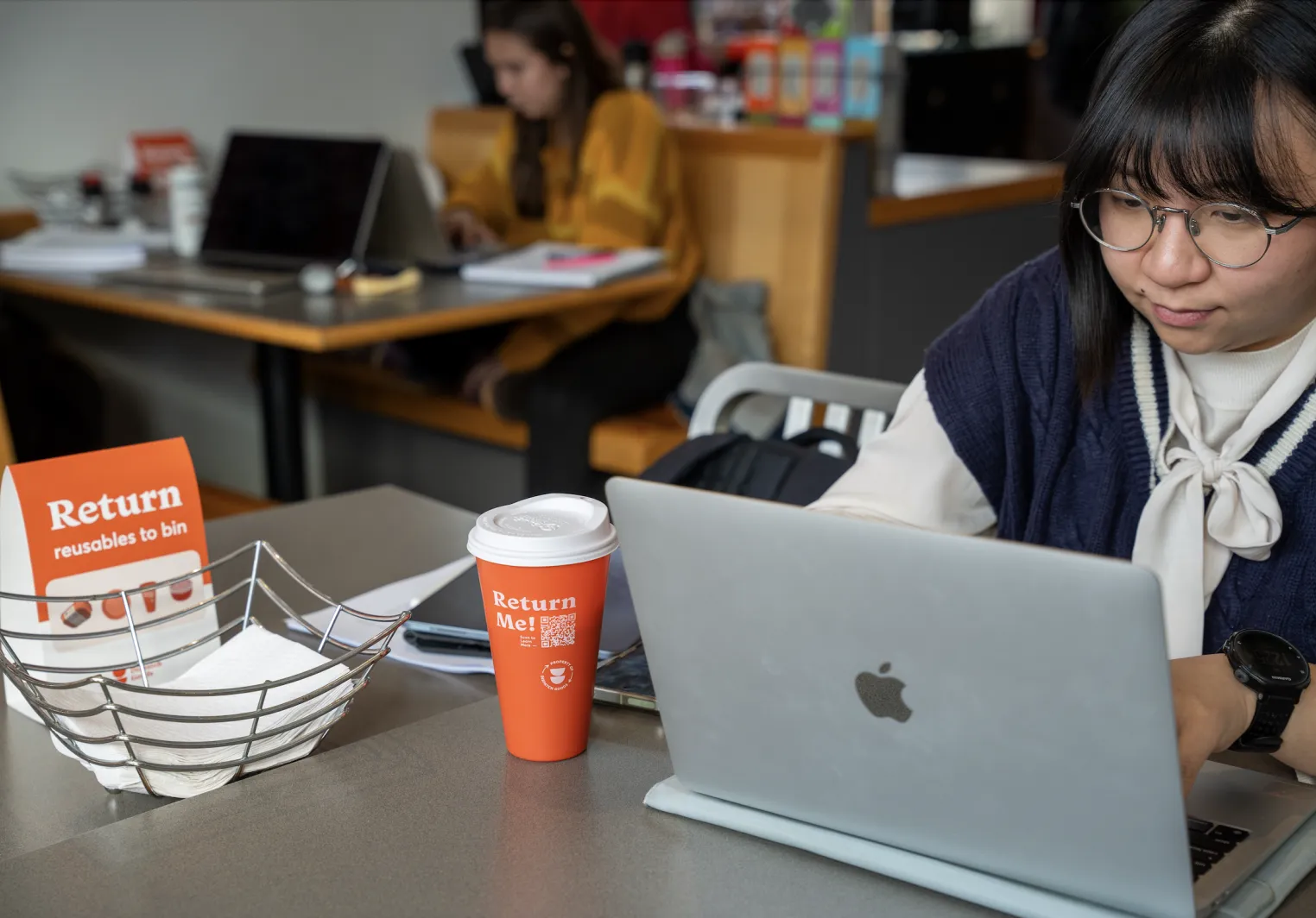 Student working with an orange cup reading "return me"