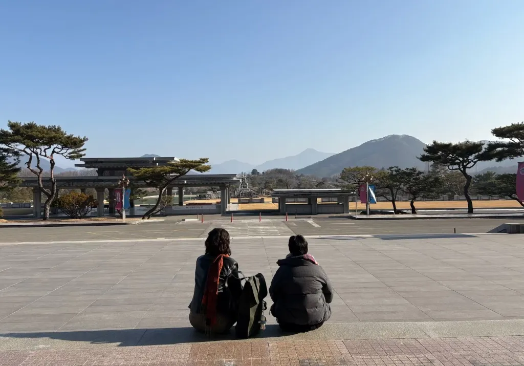 Roma and her friend sitting overlooking a Korean plaza