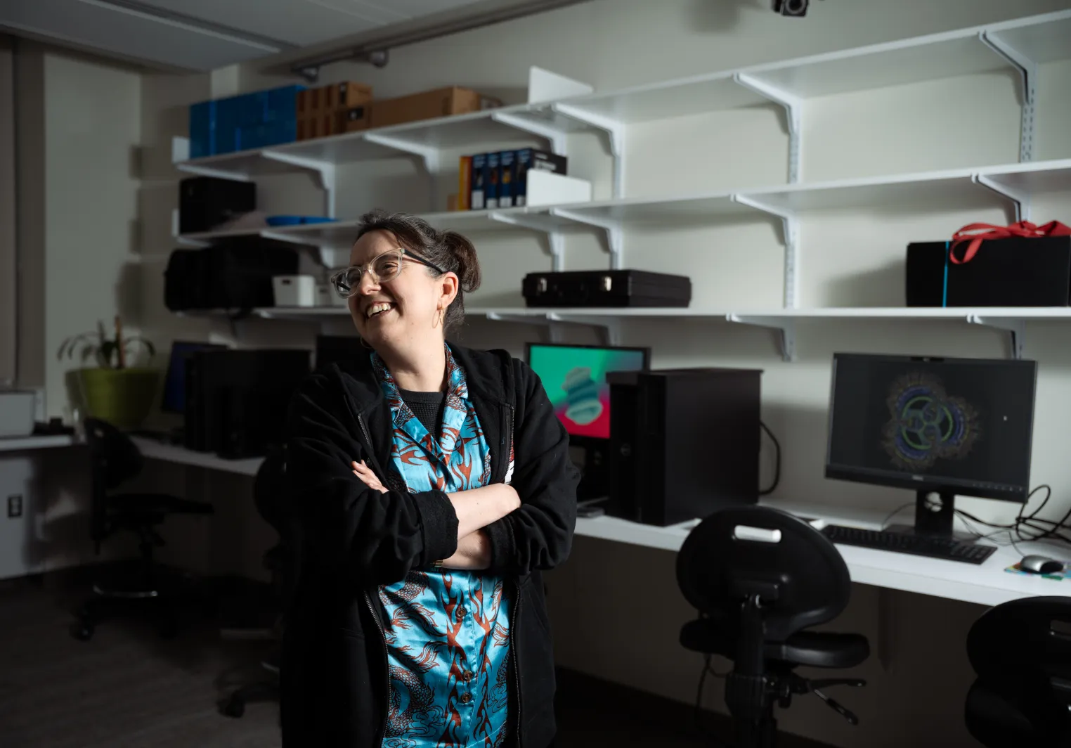 Aline Normoyle smiles with a wall of computers and shelves behind her