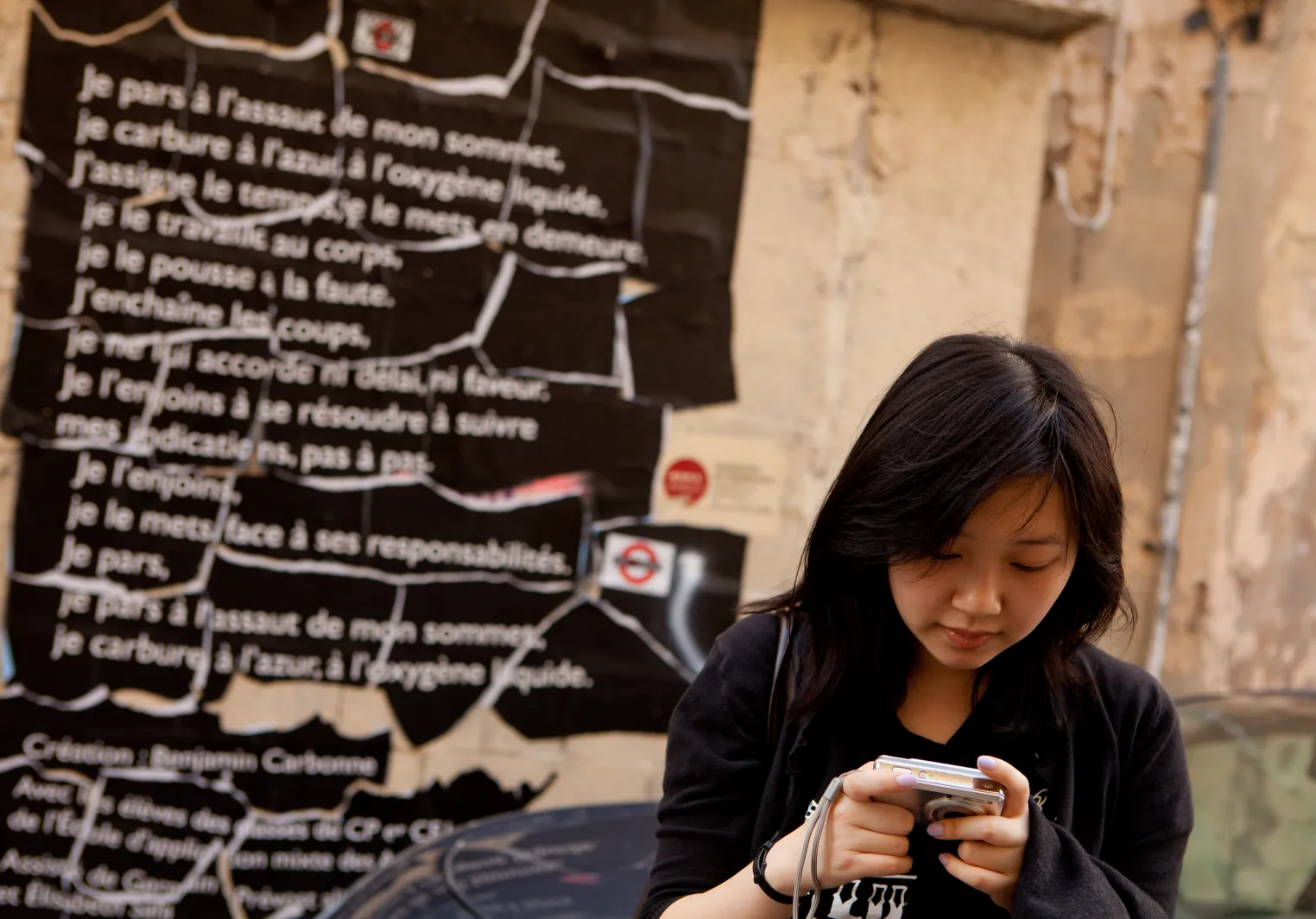 A Bryn Mawr College French and Francophone Studies Student reviews photos on a digital camera with a french subway safety poster in the background.