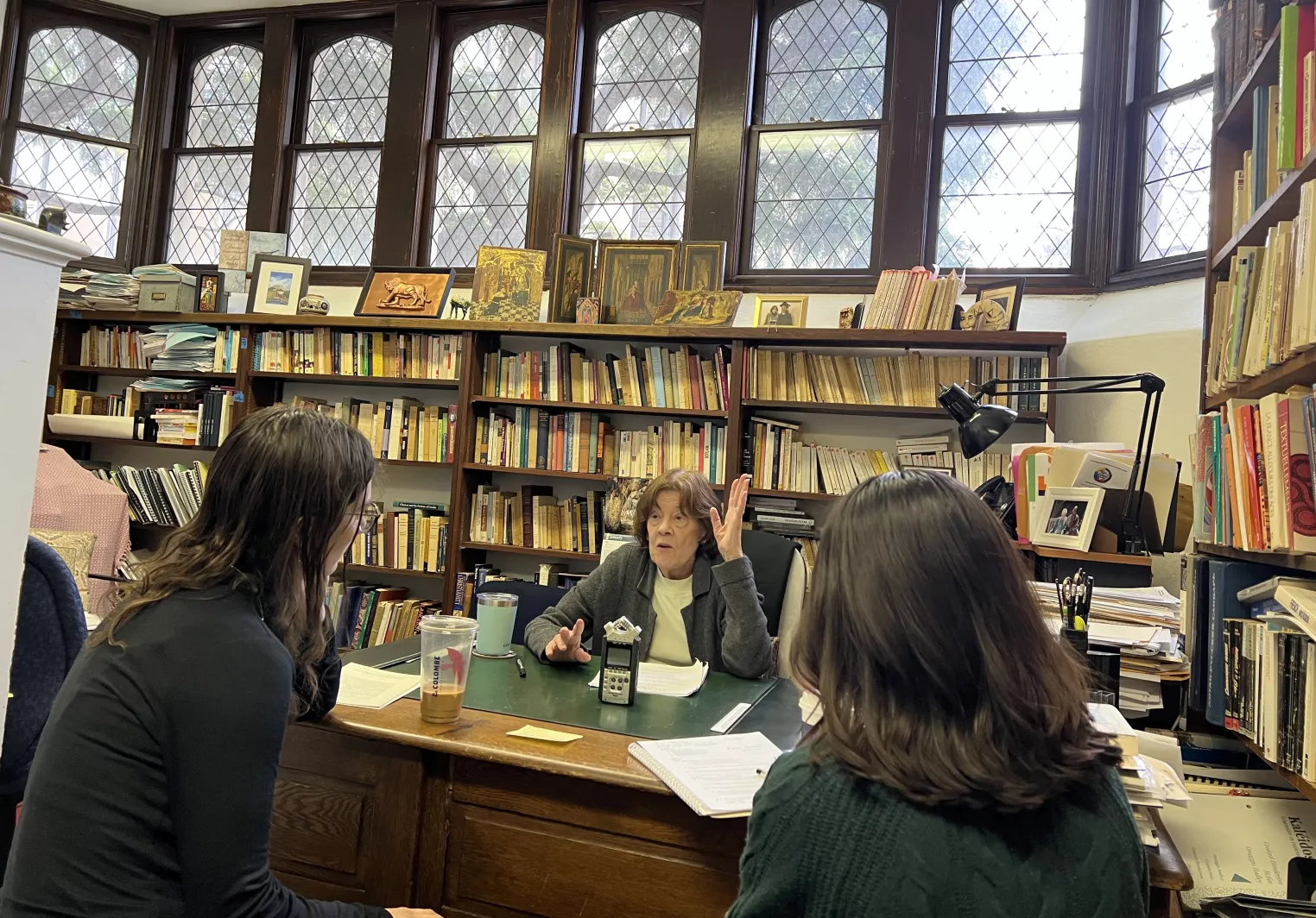 Two students interview a professor in an office in Old Library