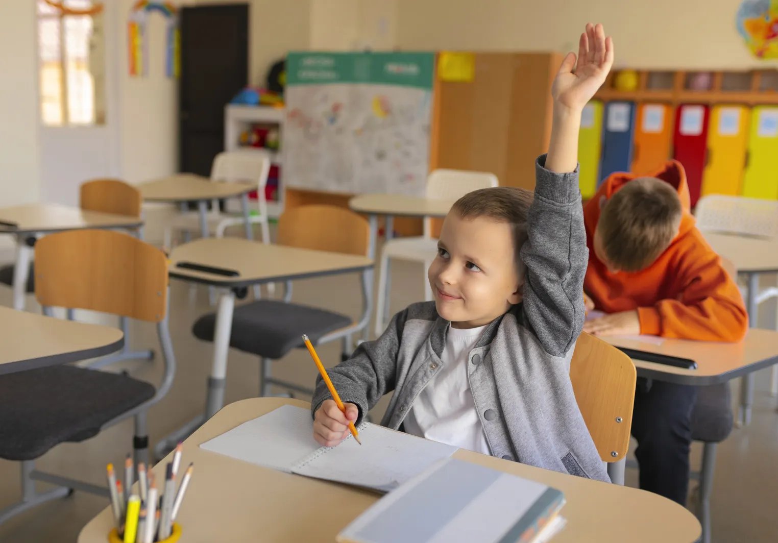 A child and family studies boy raises his hand in class