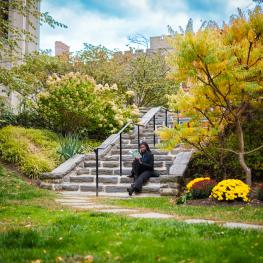 Student sitting on the steps at Taft Garden reading a book