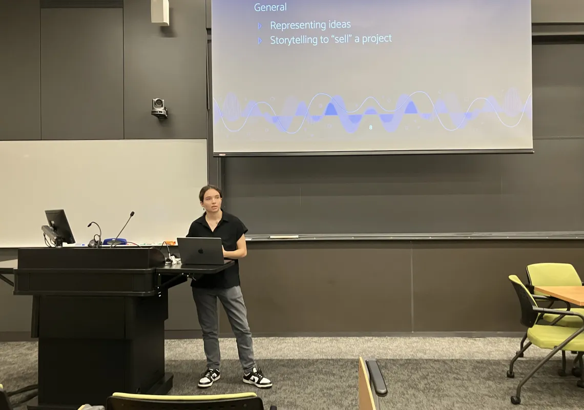 Student with a laptop presenting at the front of a classroom