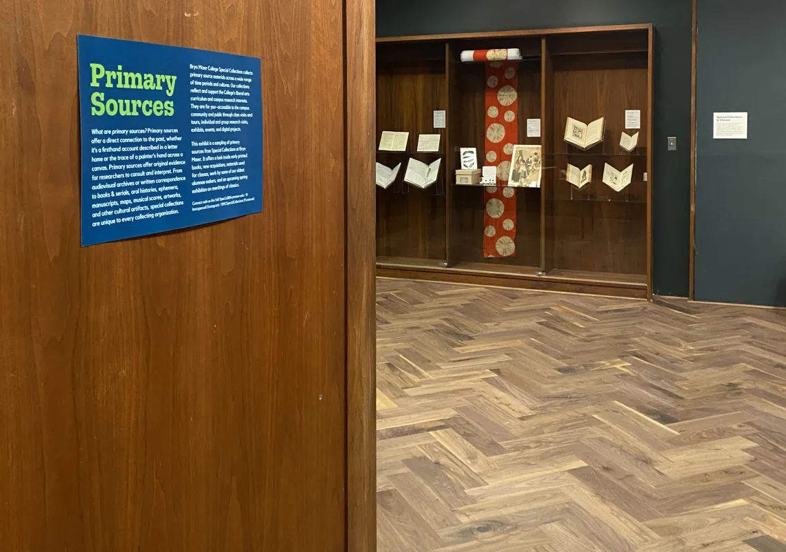 Gallery with sign saying "primary sources" and books and objects on display. 