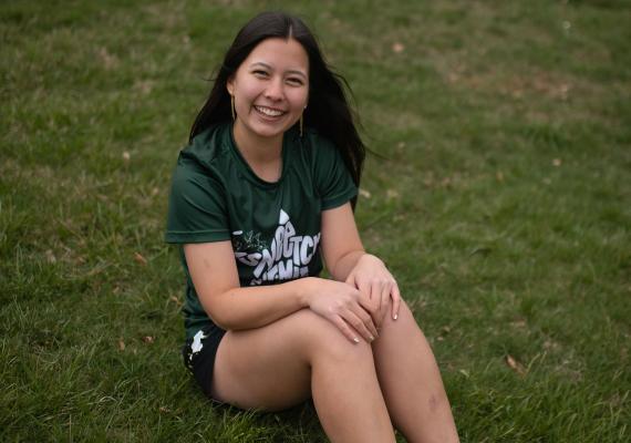 Amy Tse sitting on a field. 
