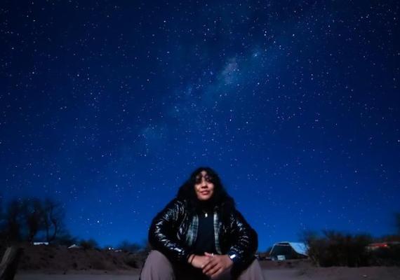 Jazmin sitting under a sky of stars. 