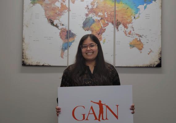 Afiya Khan standing in front of a global map. 