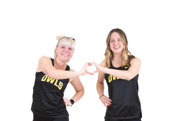 Caroline Robertson '24 and Ellie Schumacher '24 making a heart during the Track and Field media day shoot
